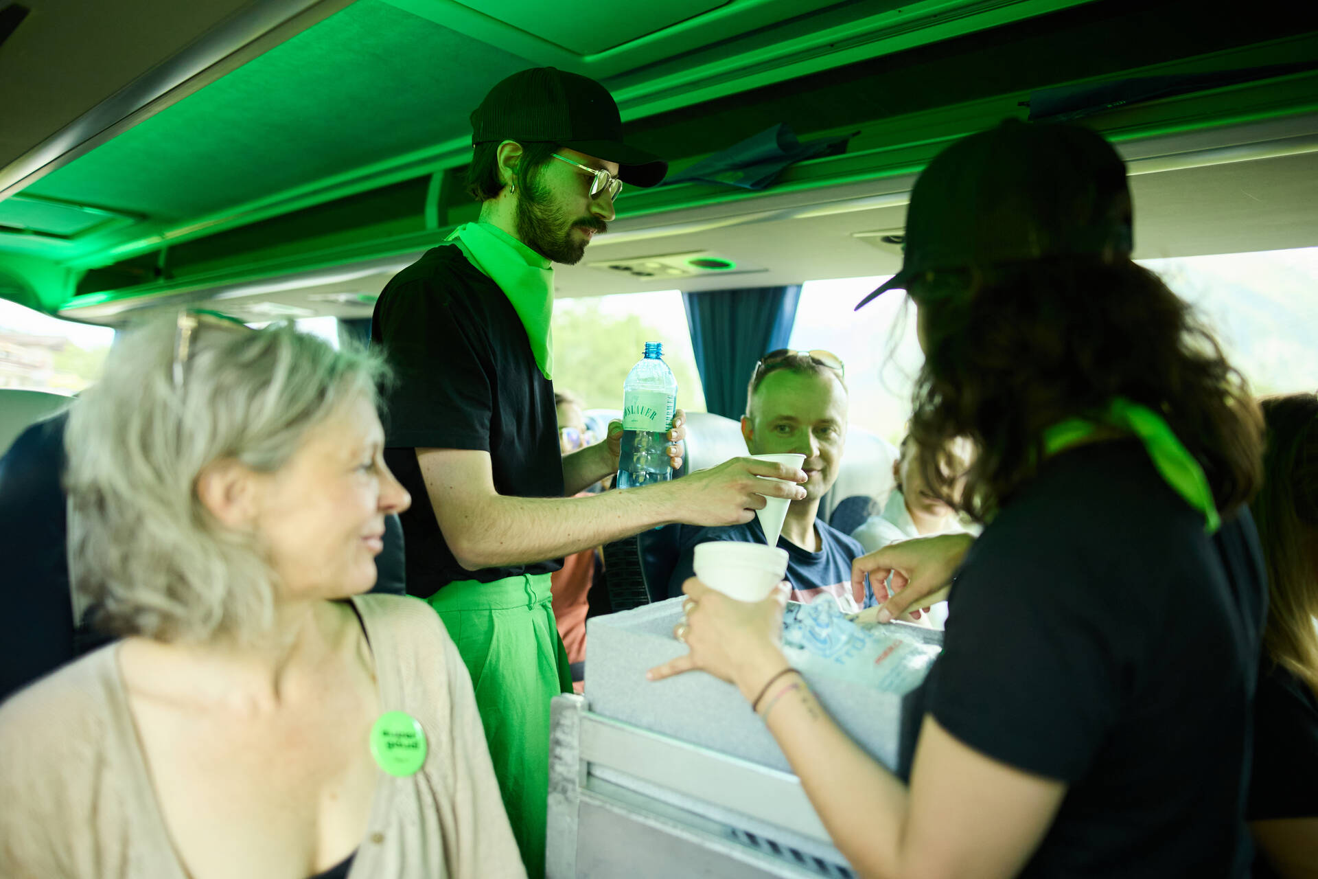 Zwei Personen schenken Wasser im Reisebus aus