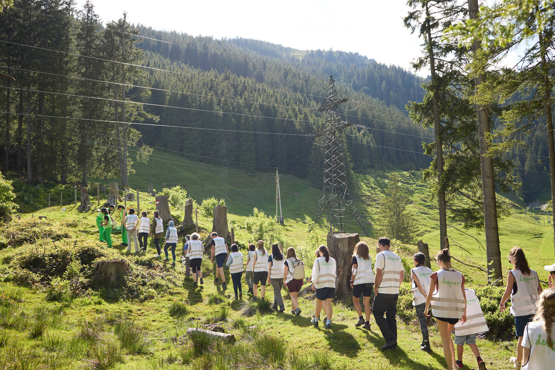 Die Gruppe geht den Hang hinauf, alle haben weisse Warnwesten an